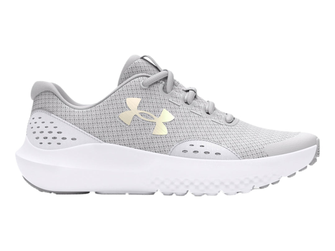 Tenis deportivos Under Armour color gris con suela blanca y logotipo dorado en el costado.