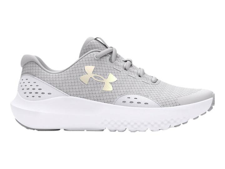 Tenis deportivos Under Armour color gris con suela blanca y logotipo dorado en el costado.