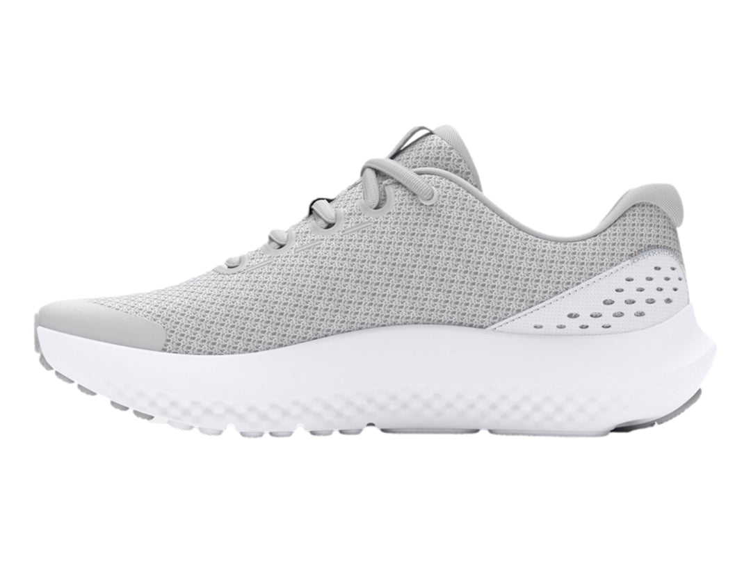 Tenis deportivos Under Armour color gris con suela blanca y logotipo dorado en el costado.