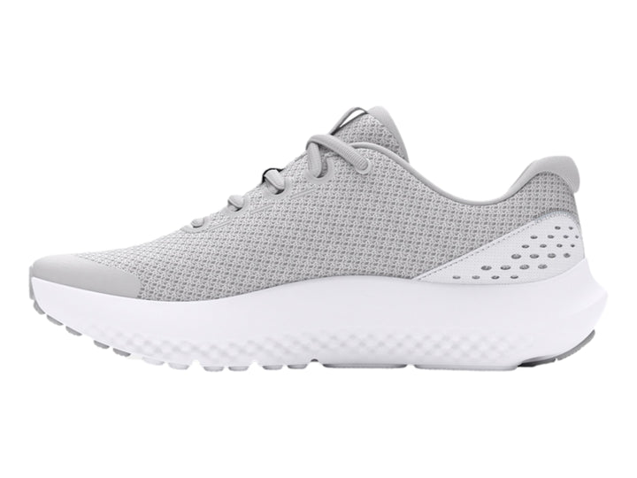 Tenis deportivos Under Armour color gris con suela blanca y logotipo dorado en el costado.
