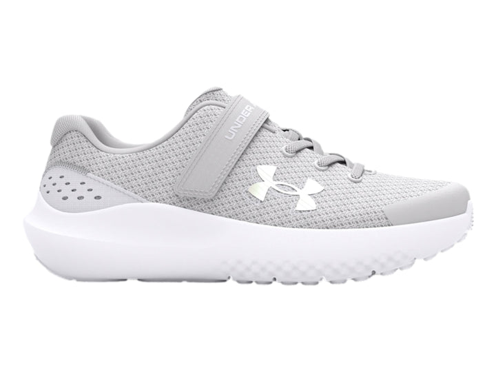 Tenis deportivos Under Armour color gris con suela blanca y correa de ajuste.