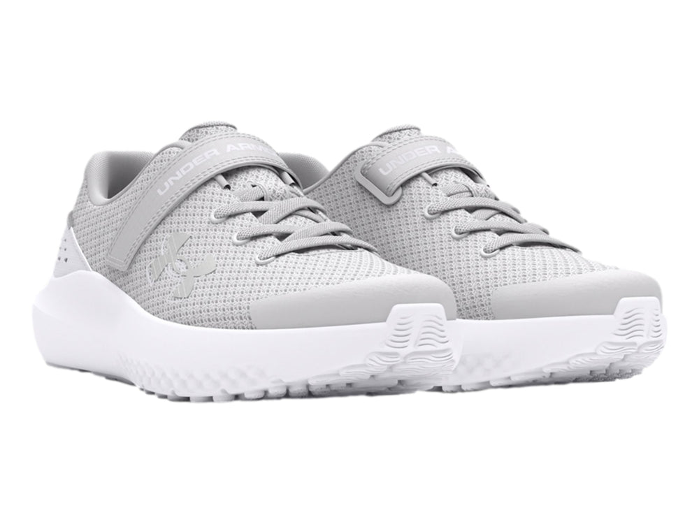 Tenis deportivos Under Armour color gris con suela blanca y correa de ajuste.