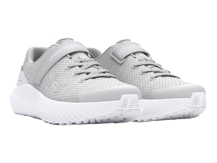 Tenis deportivos Under Armour color gris con suela blanca y correa de ajuste.