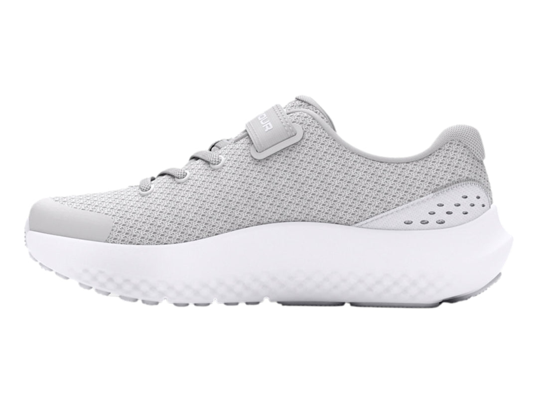 Tenis deportivos Under Armour color gris con suela blanca y correa de ajuste.