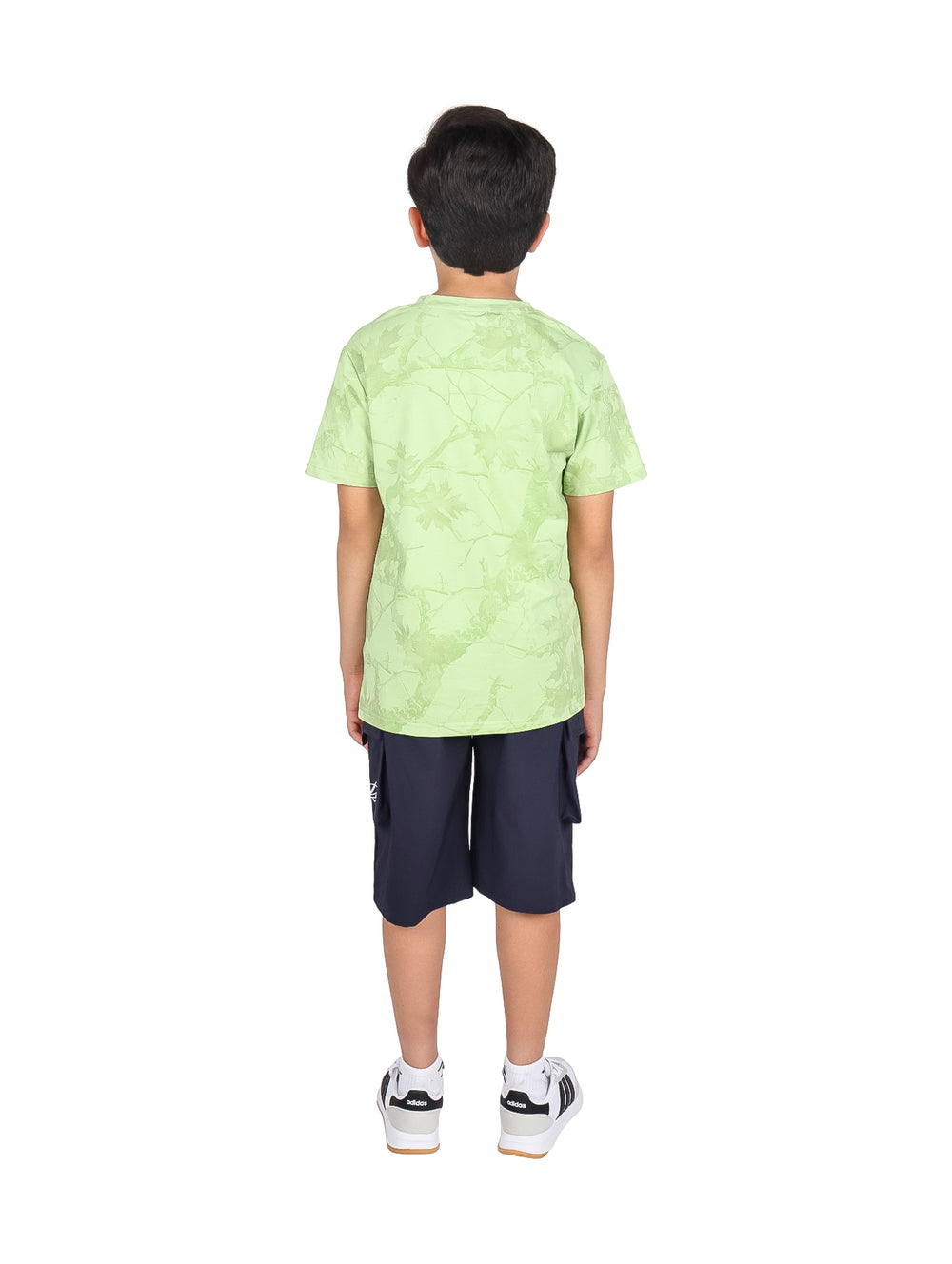 Niño modelando un conjunto de camiseta verde claro y shorts negros.