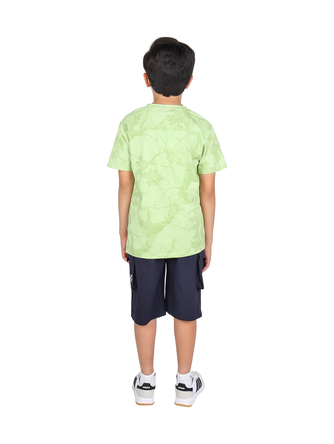 Niño modelando un conjunto de camiseta verde claro y shorts negros.