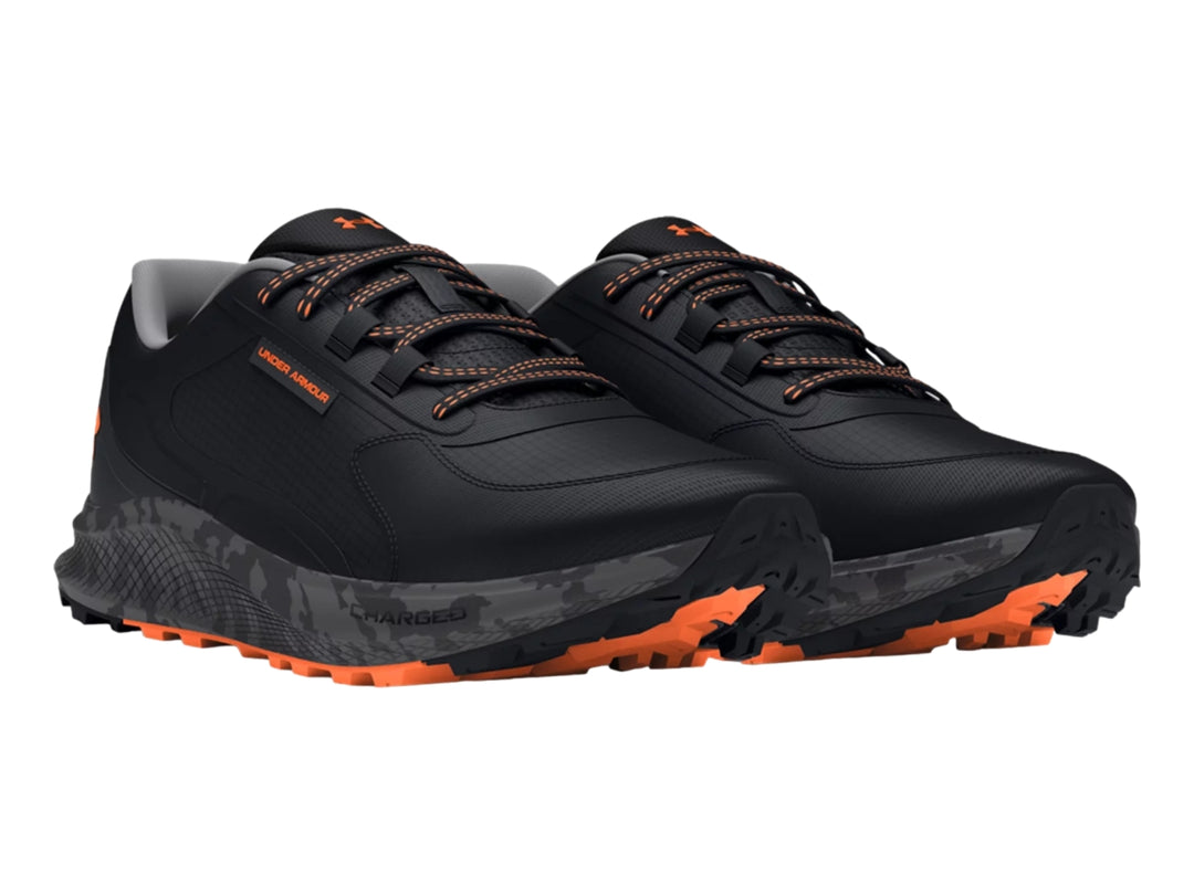 Tenis deportivos Under Armour color negro con detalles en naranja y suela gris.