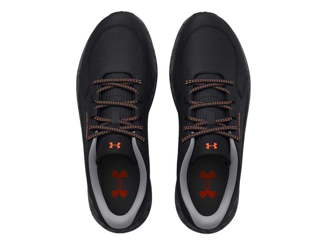 Tenis deportivos Under Armour color negro con detalles en naranja y suela gris.