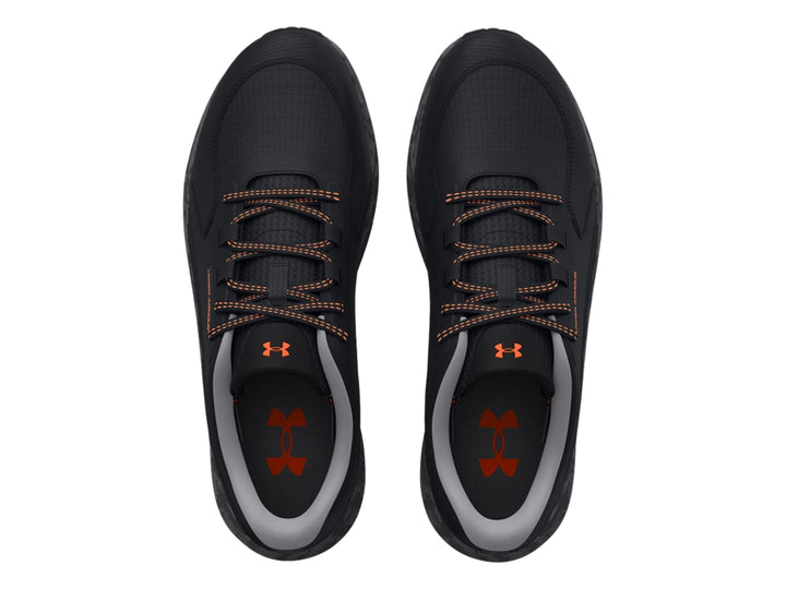 Tenis deportivos Under Armour color negro con detalles en naranja y suela gris.
