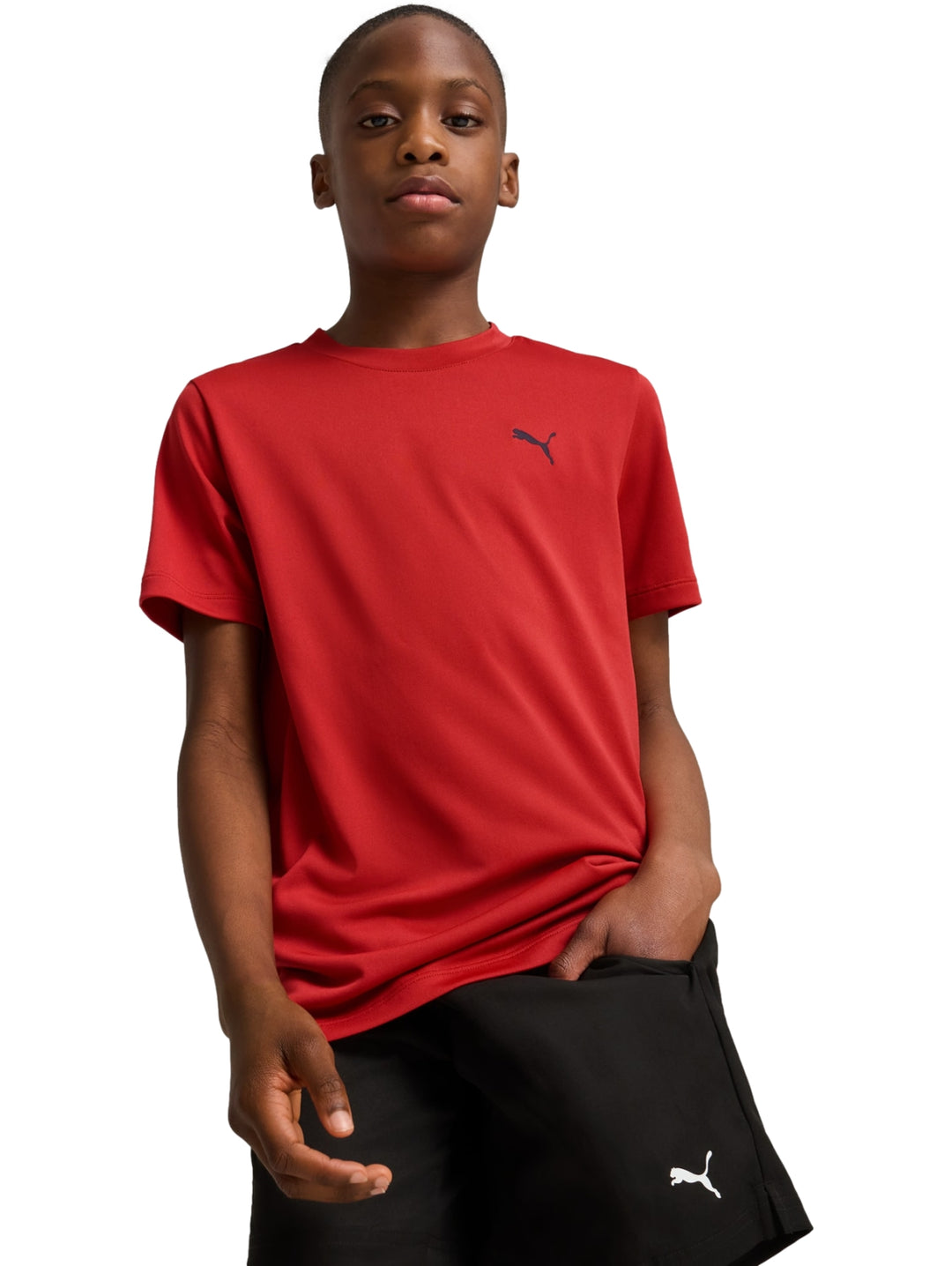 Niño vistiendo playera roja de manga corta marca Puma y shorts negros sobre fondo blanco.