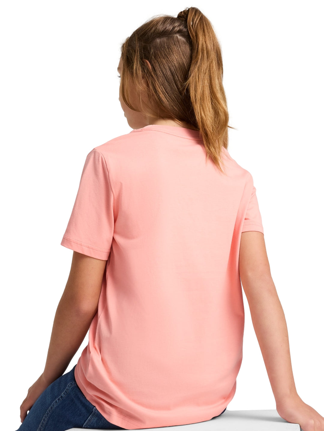 Niña vistiendo una playera Puma de color rosa con logotipo en el pecho y pantalones de mezclilla azules.