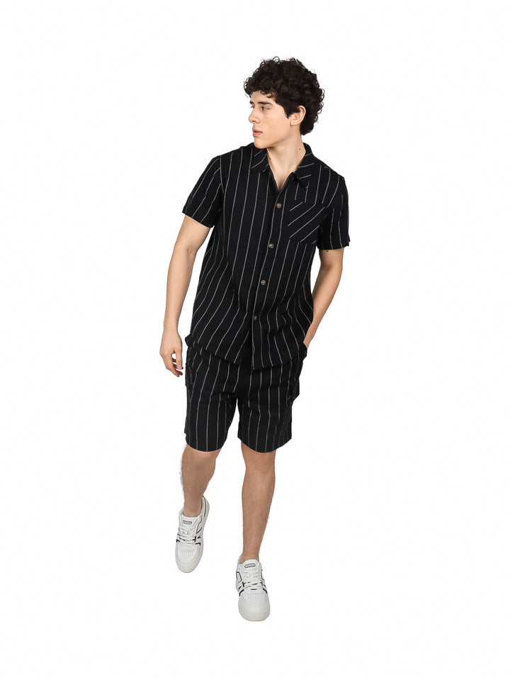 Hombre vistiendo conjunto de camisa y shorts negros con rayas verticales blancas.