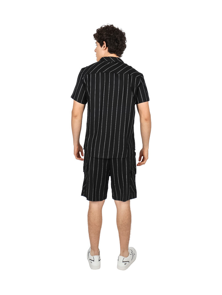 Hombre vistiendo conjunto de camisa y shorts negros con rayas verticales blancas.