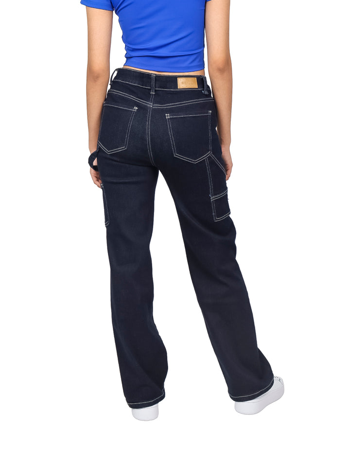 Mujer vistiendo pantalones jeans rectos color azul oscuro con costuras blancas contrastantes.