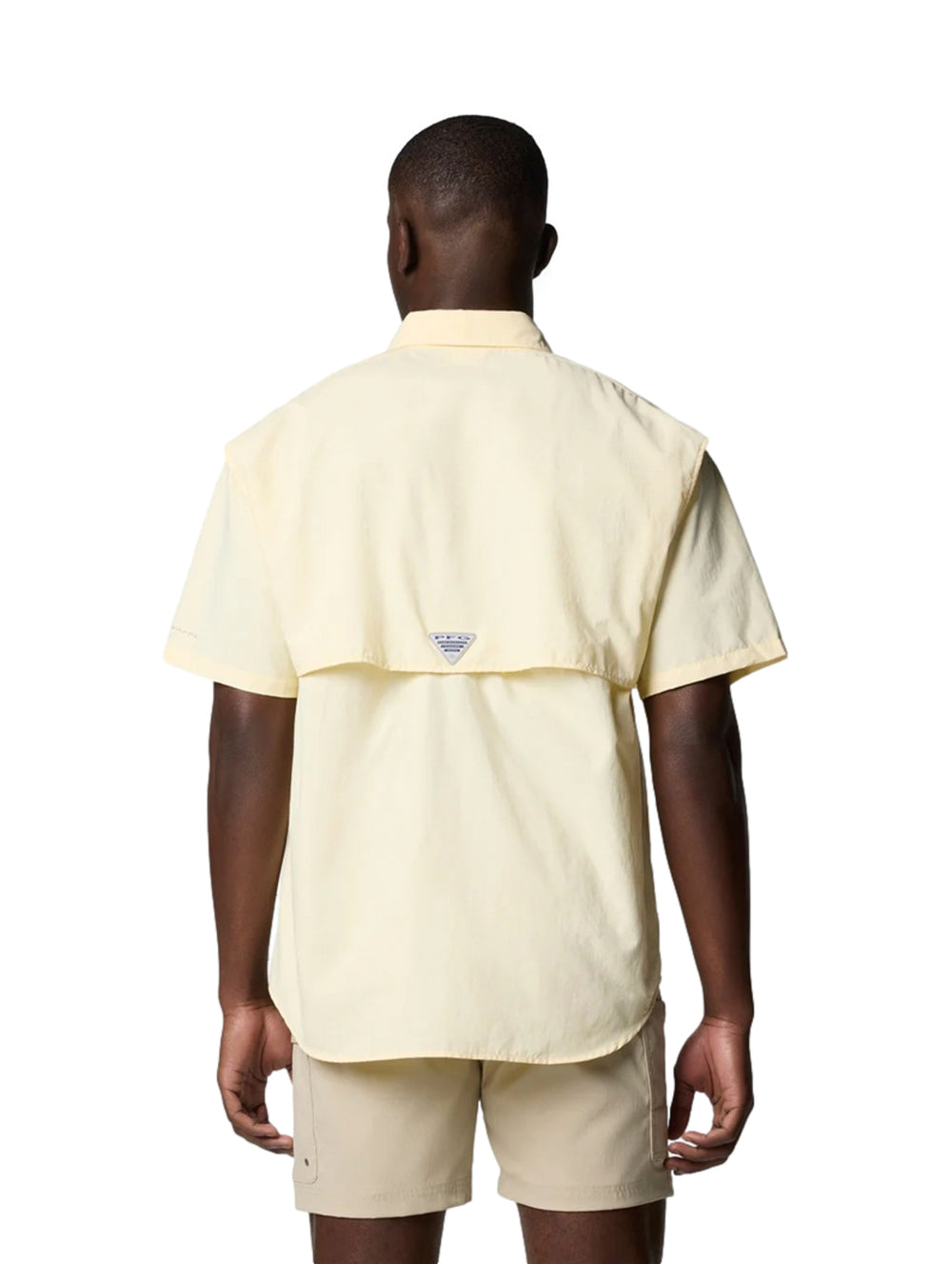 Hombre vistiendo una camisa Columbia de manga corta color amarillo pálido con dos bolsillos en el pecho.