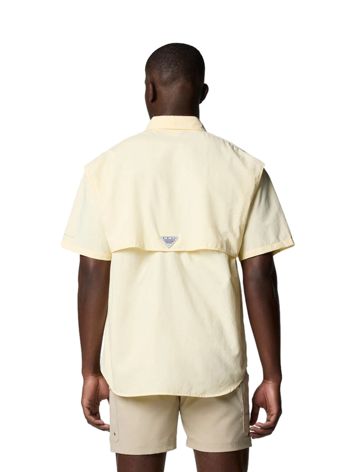 Hombre vistiendo una camisa Columbia de manga corta color amarillo pálido con dos bolsillos en el pecho.