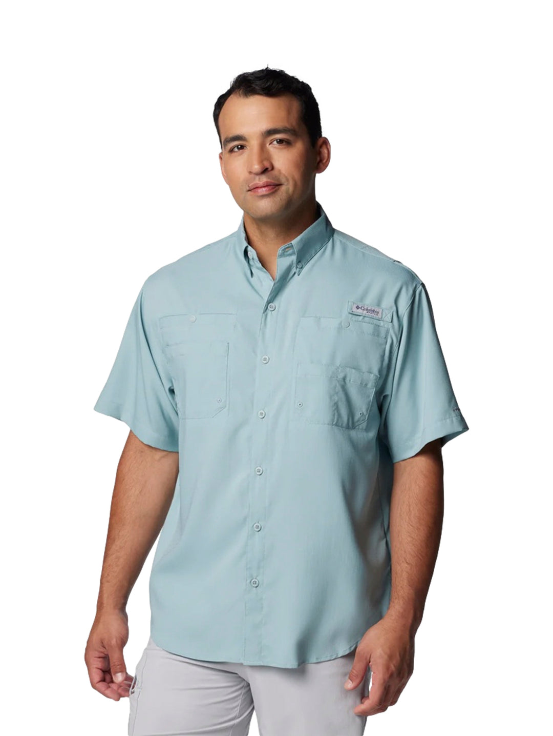 Hombre vistiendo una camisa Columbia de manga corta en color azul claro con bolsillos frontales.