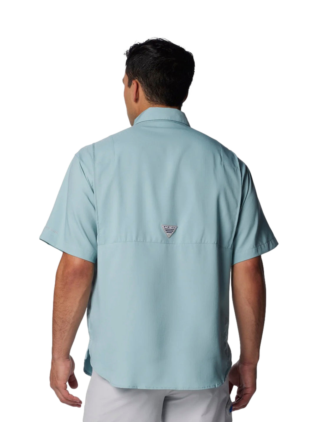 Hombre vistiendo una camisa Columbia de manga corta en color azul claro con bolsillos frontales.