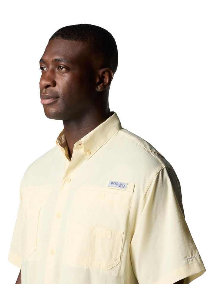 Hombre vistiendo una camisa Columbia de manga corta en color amarillo pálido con bolsillos frontales.