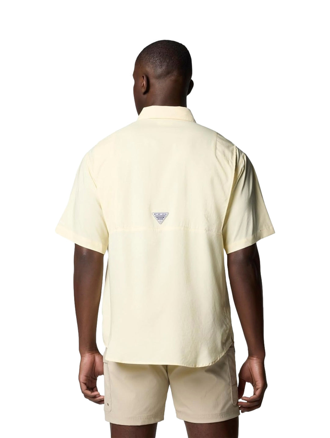 Hombre vistiendo una camisa Columbia de manga corta en color amarillo pálido con bolsillos frontales.
