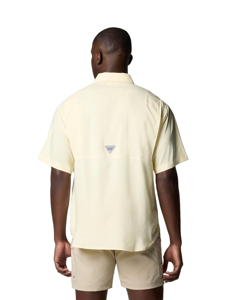 Hombre vistiendo una camisa Columbia de manga corta en color amarillo pálido con bolsillos frontales.