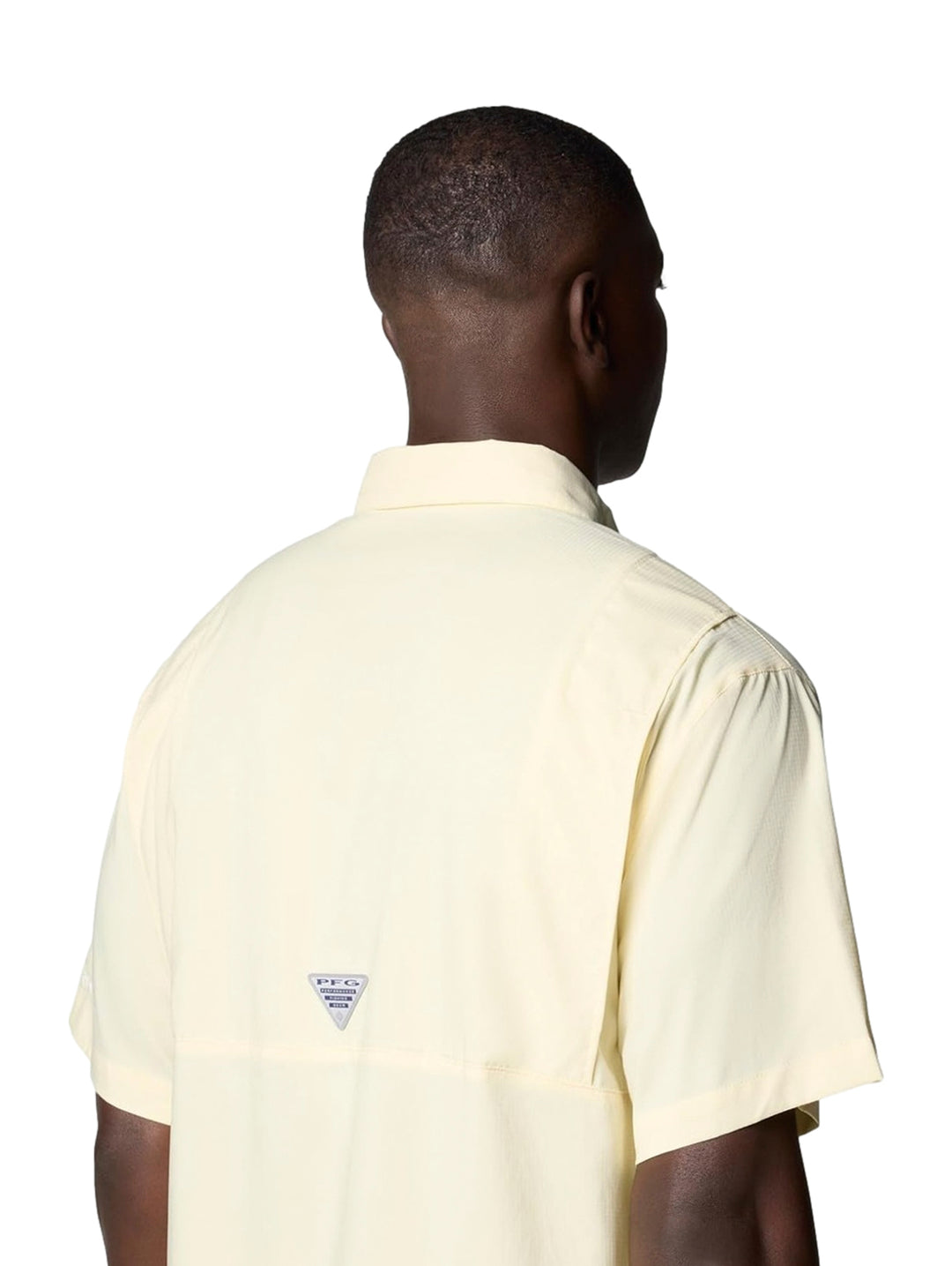 Hombre vistiendo una camisa Columbia de manga corta en color amarillo pálido con bolsillos frontales.