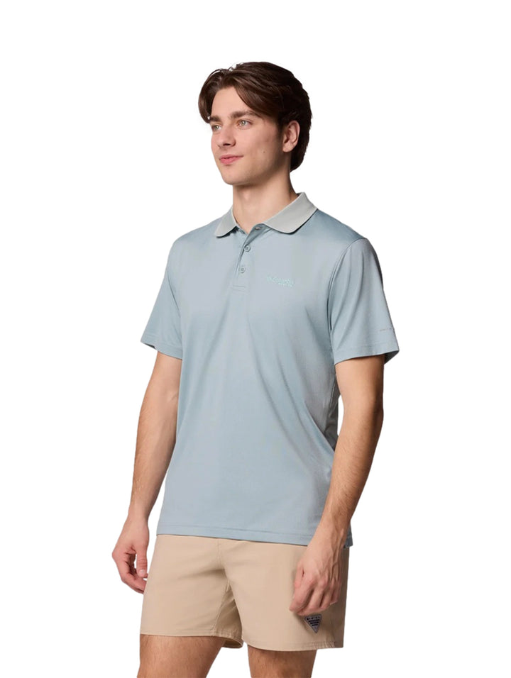 Hombre vistiendo una camiseta polo Columbia de color azul claro con cuello gris y pantalones beige.