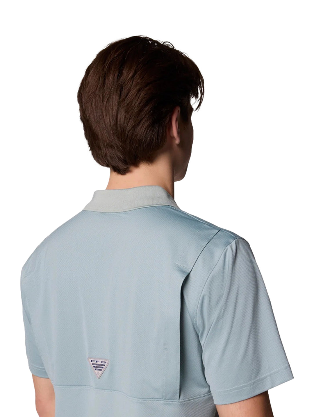 Hombre vistiendo una camiseta polo Columbia de color azul claro con cuello gris y pantalones beige.