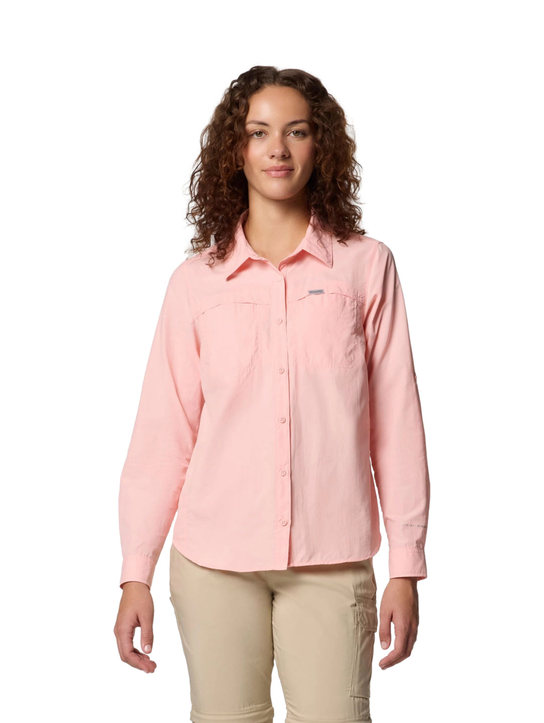 Mujer vistiendo una camisa Columbia de manga larga en color rosa sand con bolsillos frontales.