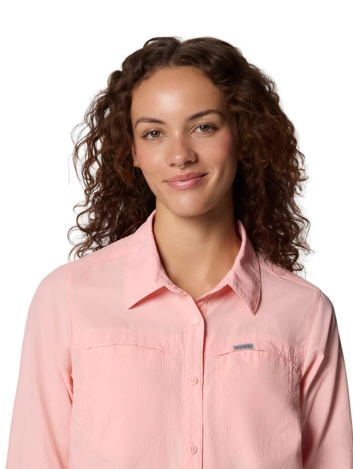 Mujer vistiendo una camisa Columbia de manga larga en color rosa sand con bolsillos frontales.
