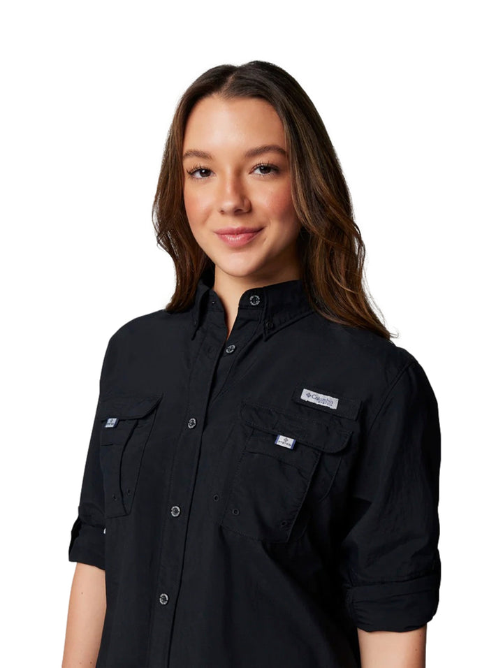 Mujer vistiendo una camisa Columbia PFG de manga larga en color negro con botones y bolsillos frontales.