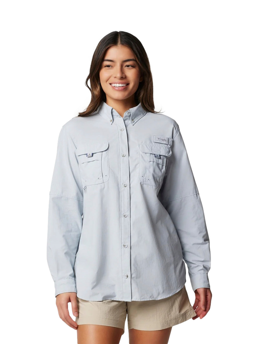 Mujer vistiendo una camisa Columbia de manga larga en color gris claro con bolsillos frontales.