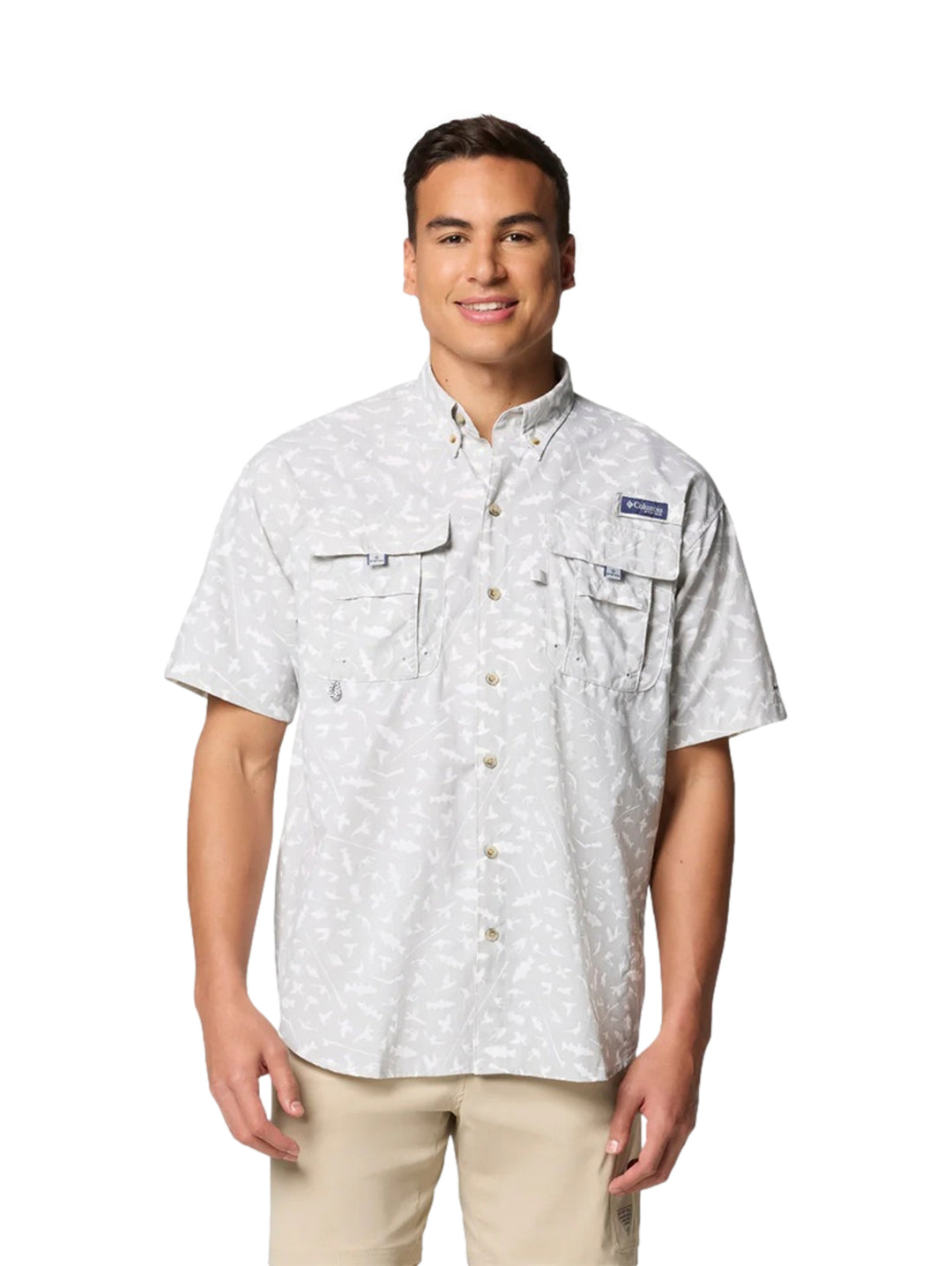 Hombre vistiendo camisa Columbia de manga corta color gris claro con estampado sutil y bolsillos frontales.
