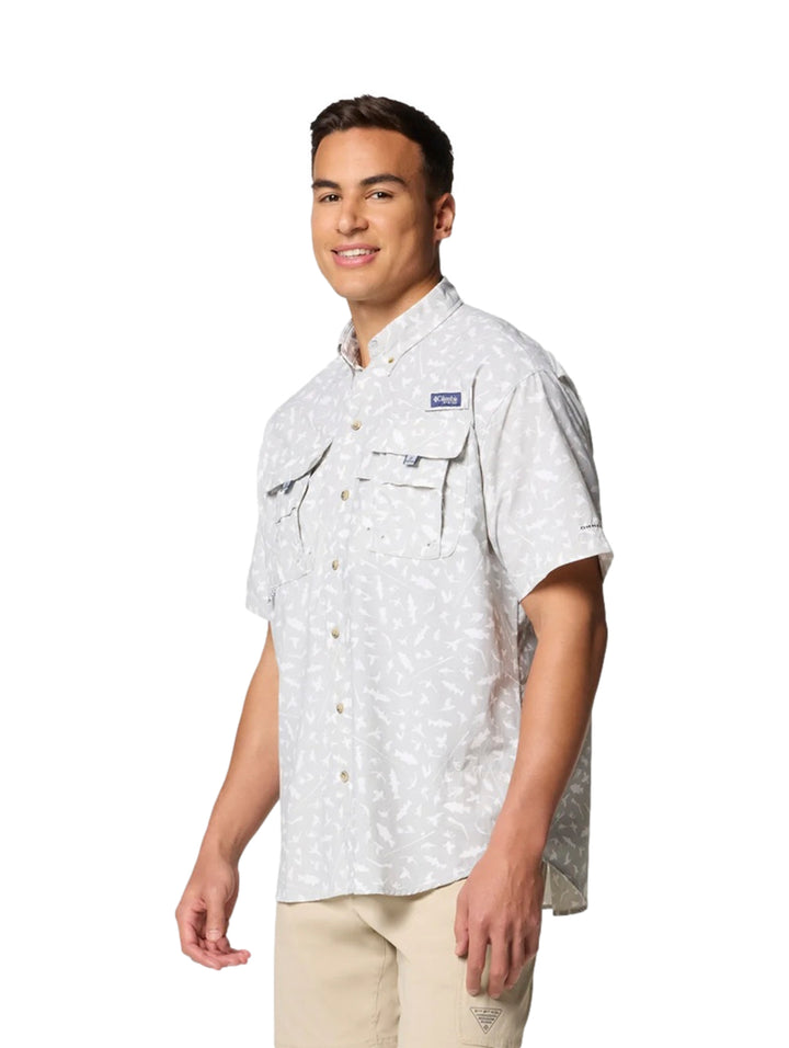 Hombre vistiendo camisa Columbia de manga corta color gris claro con estampado sutil y bolsillos frontales.