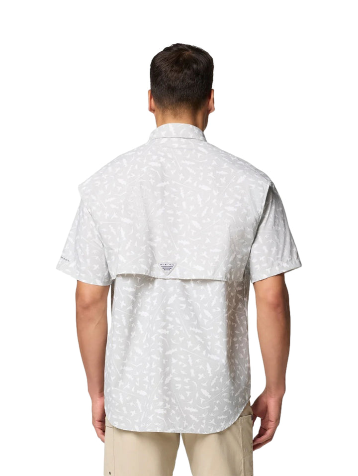 Hombre vistiendo camisa Columbia de manga corta color gris claro con estampado sutil y bolsillos frontales.
