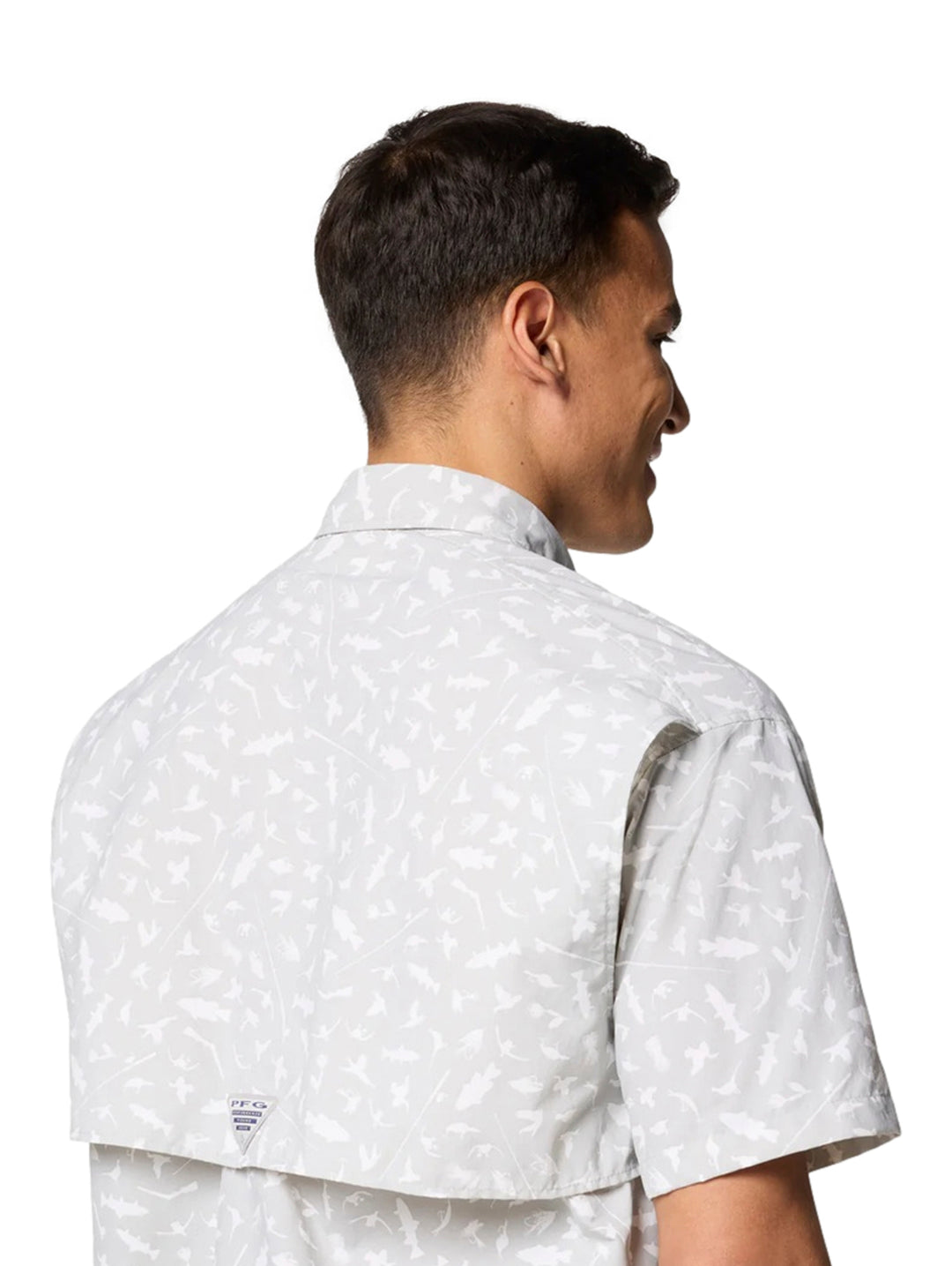 Hombre vistiendo camisa Columbia de manga corta color gris claro con estampado sutil y bolsillos frontales.