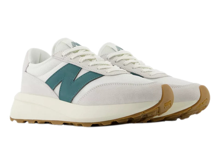 Tenis New Balance blancos con logo verde azulado y suela de goma color café.