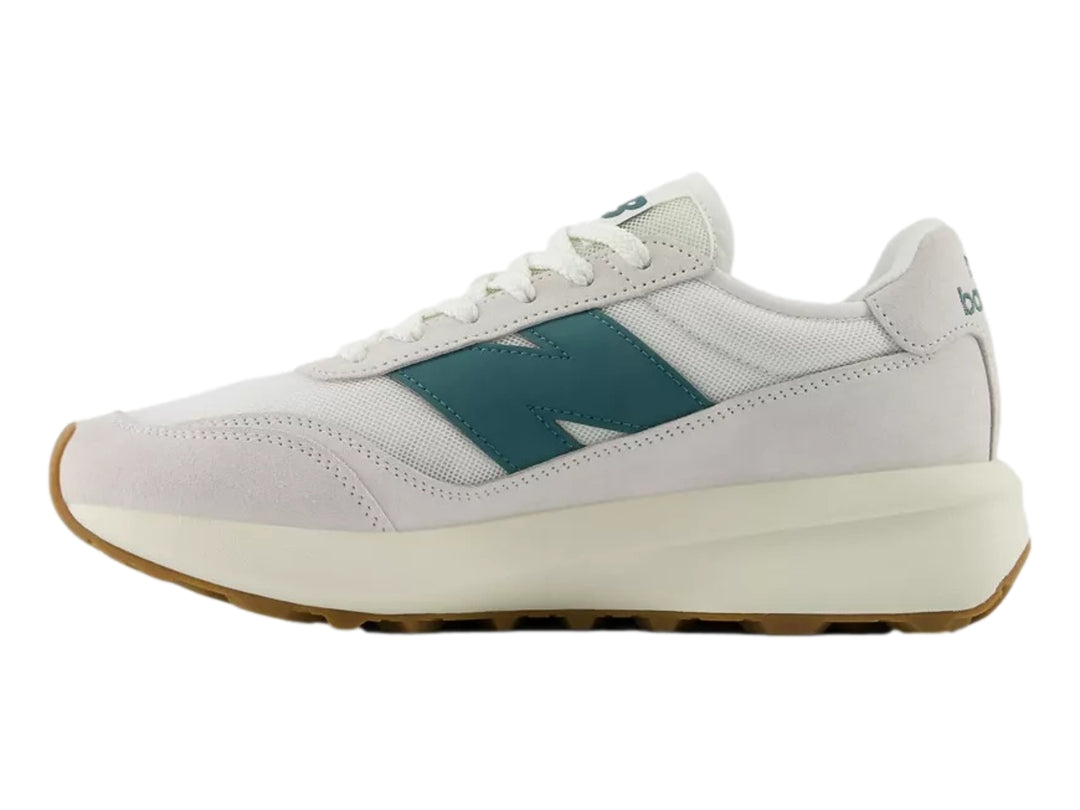 Tenis New Balance blancos con logo verde azulado y suela de goma color café.