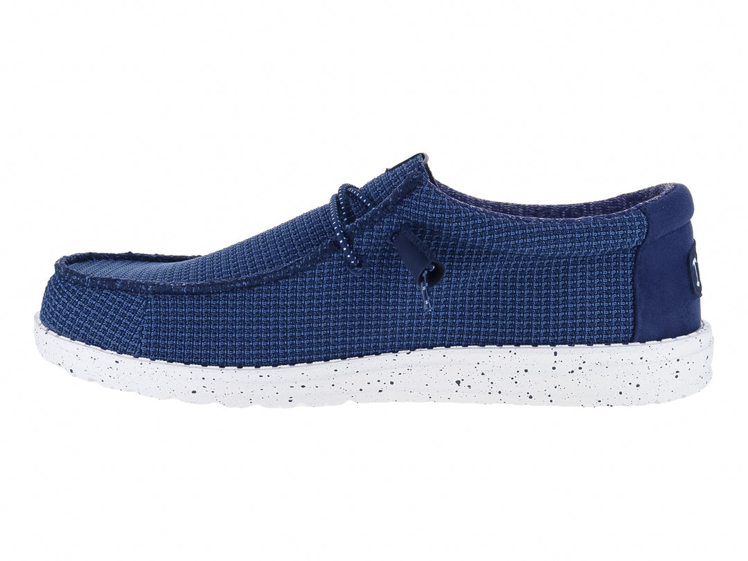 Zapato plano Hey Dude Wally Sport Mesh en color navy con suela blanca moteada y detalles en naranja.