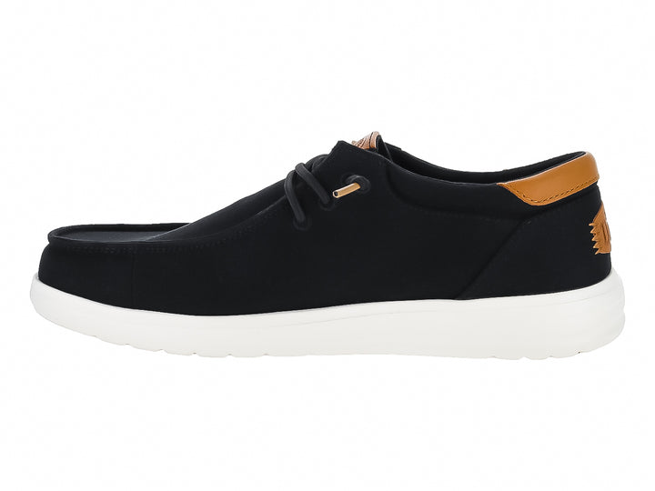 Zapato casual Hey Dude Paul de lona color negro con suela blanca y detalle café en el talón.