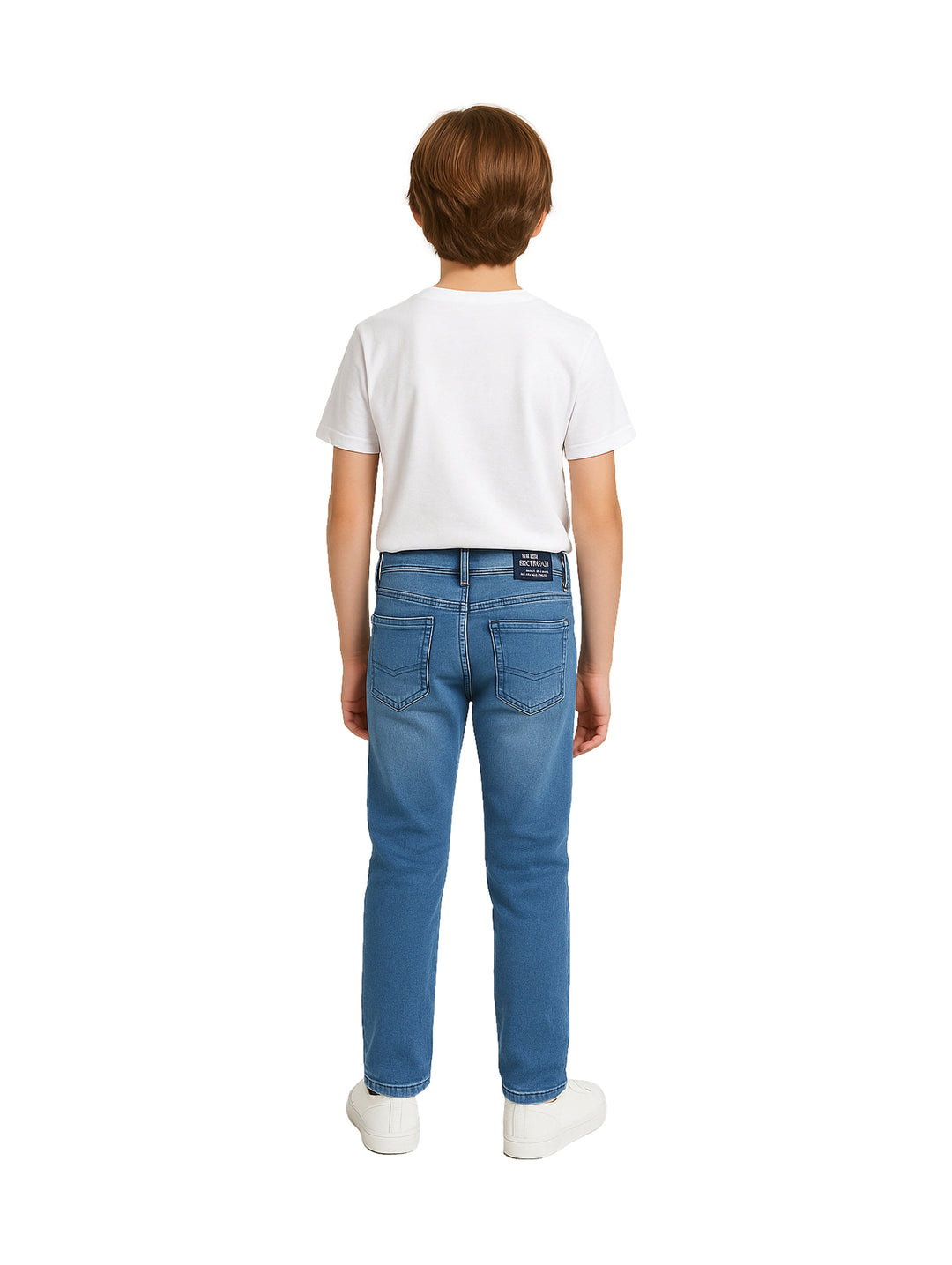 Niño vistiendo pantalón de mezclilla azul, camiseta blanca y tenis blancos.