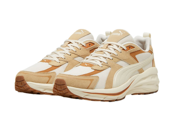 Tenis PUMA en color blanco y beige con suela gruesa y detalles de malla.