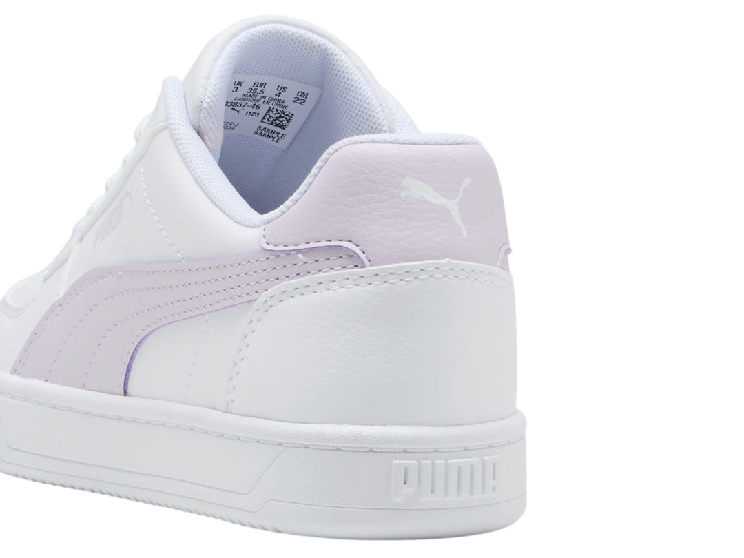 Tenis PUMA blancos con franja lateral y talón en color lila, diseño casual y suela blanca.
