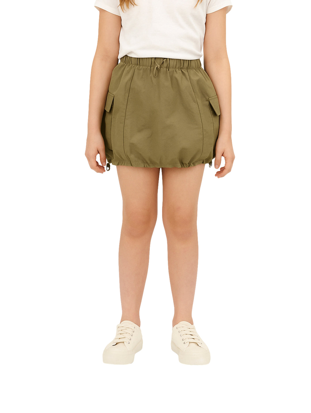 Niña vistiendo una falda corta de color olivo con bolsillos laterales tipo cargo y cintura elástica.