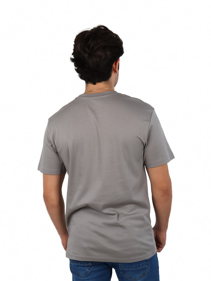 Hombre vistiendo una playera gris de manga corta y cuello redondo.