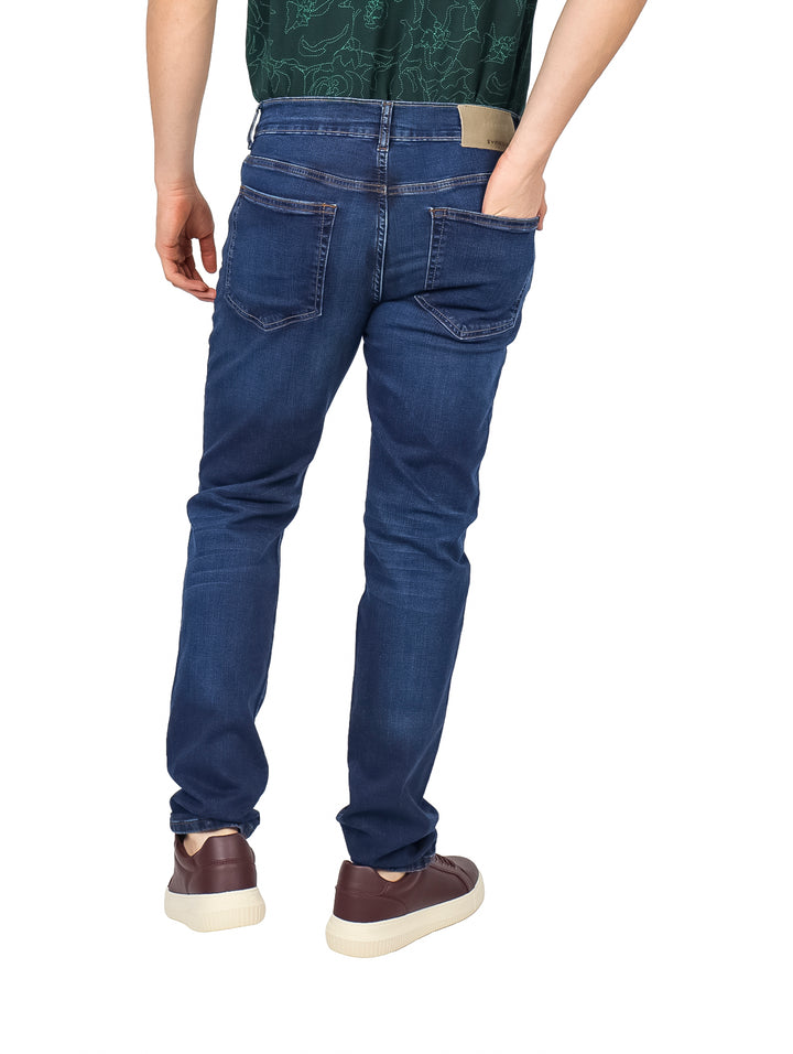 Hombre vistiendo jeans de mezclilla color azul claro con corte ajustado y calzado casual marrón.