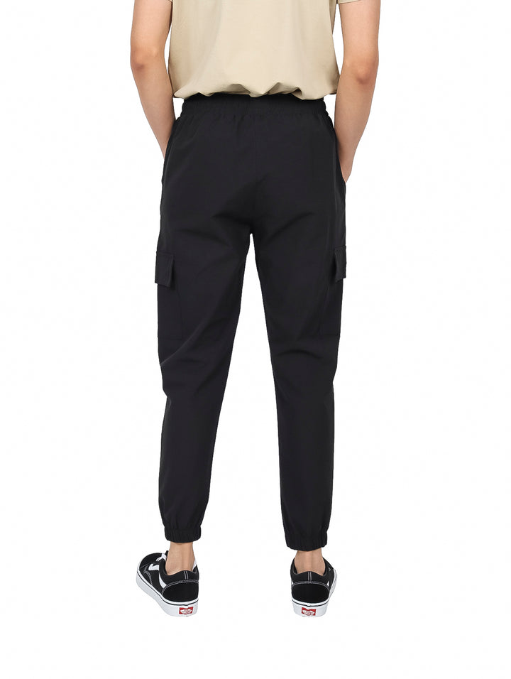 Hombre vistiendo pantalones jogger color negro con bolsillos laterales y cintura ajustable.