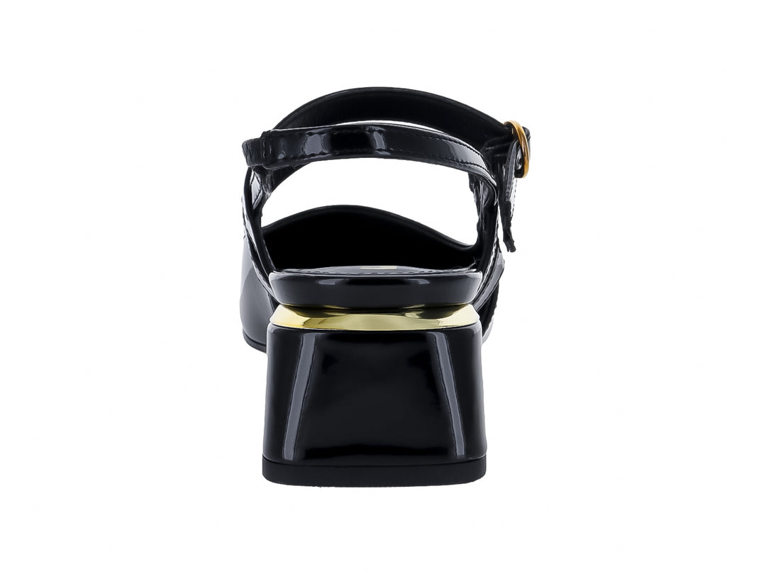 Zapato negro de charol con punta fina, tacón cuadrado y hebillas doradas.
