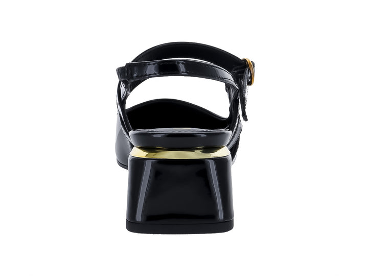 Zapato negro de charol con punta fina, tacón cuadrado y hebillas doradas.