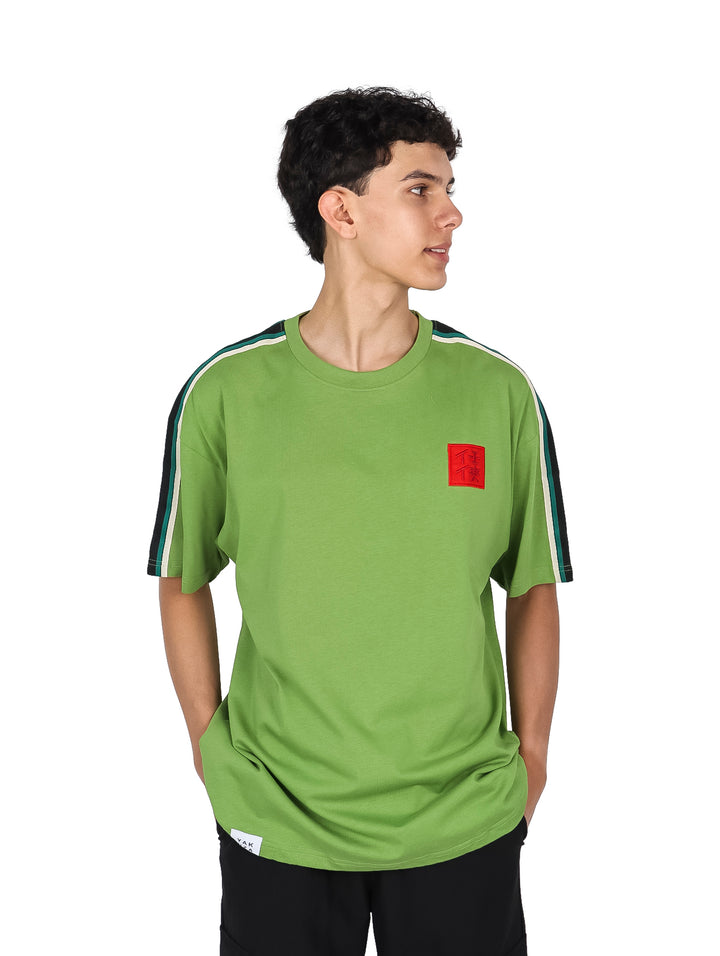 Hombre vistiendo playera color verde con franjas blancas y negras en las mangas y un pequeño detalle rojo al pecho.